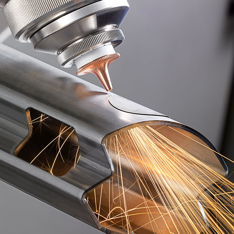 Cận cảnh đầu cắt laser fiber đang gia công đường cắt và rãnh kỹ thuật trên ống kim loại