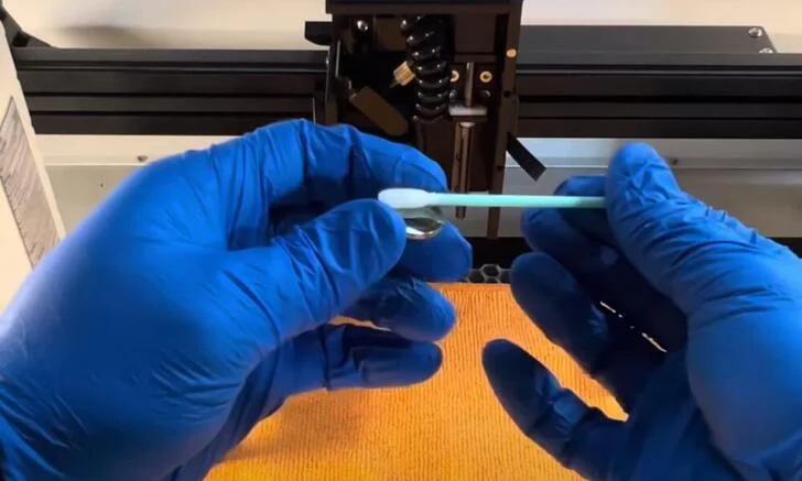 Kỹ thuật viên vệ sinh kính bảo vệ và kiểm tra đầu cắt máy laser Fiber